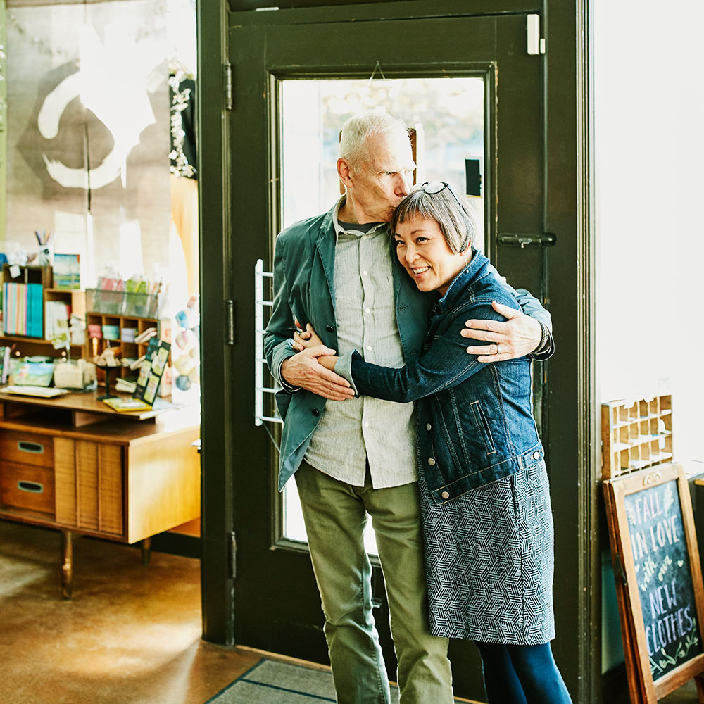 Couple embrace in doorway of local clothing store