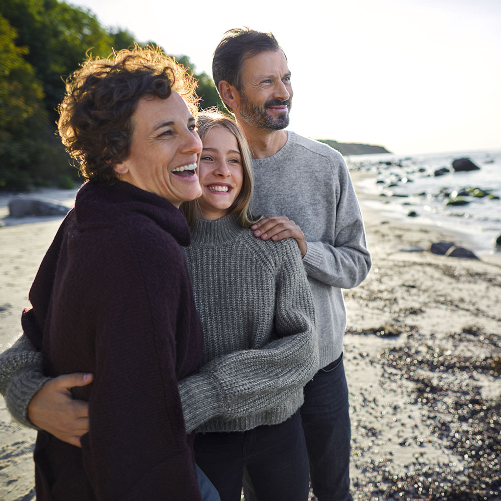 family watching the sunset on a rocky beach
