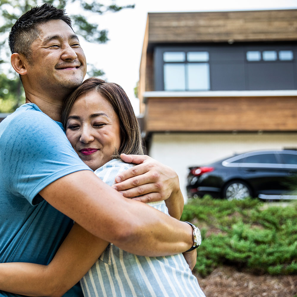 man embraces woman outside a modern home