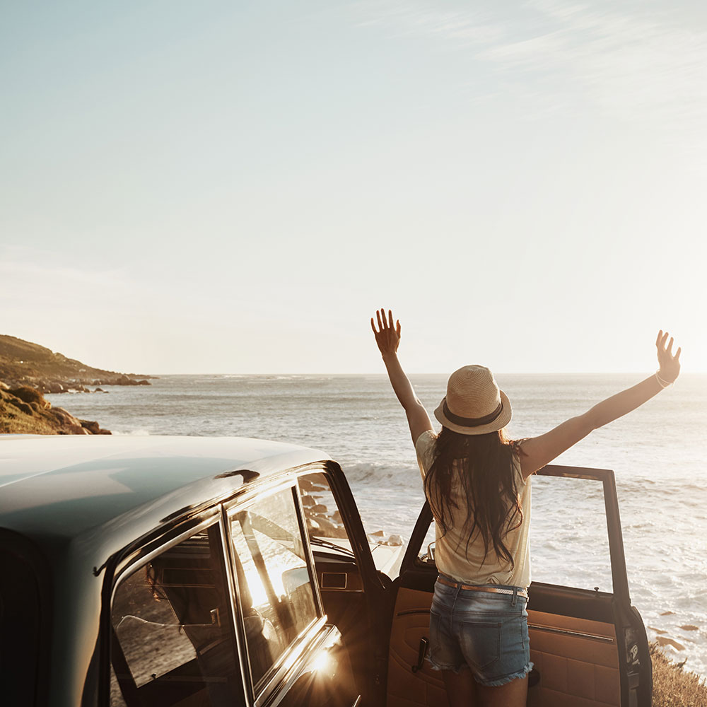 Woman car passenger embracing the sun on the beach