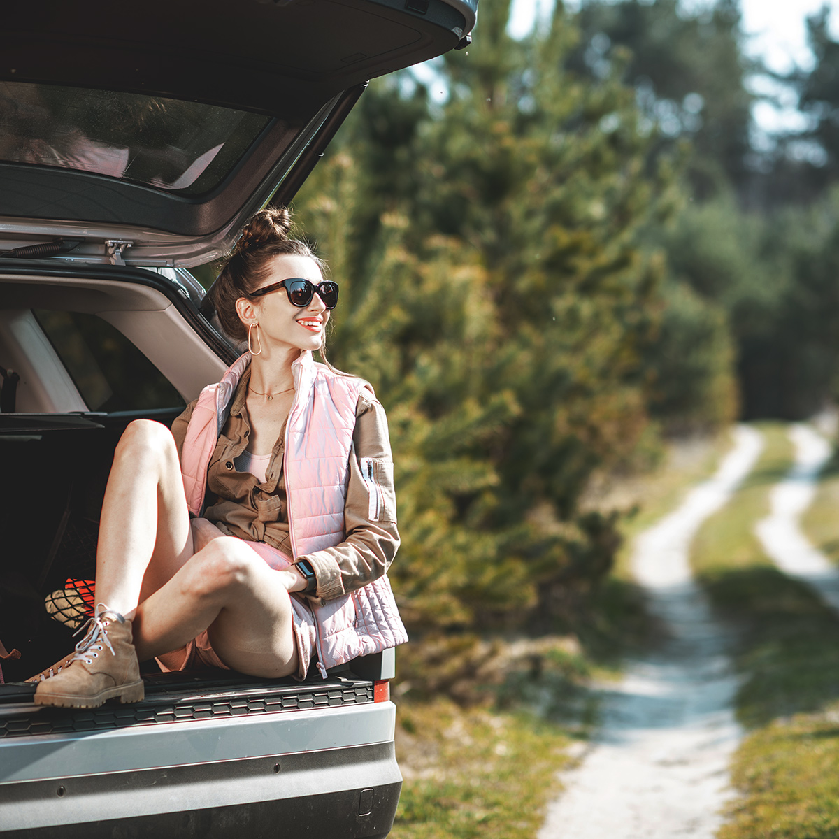 Woman sitting in rear hatch of car