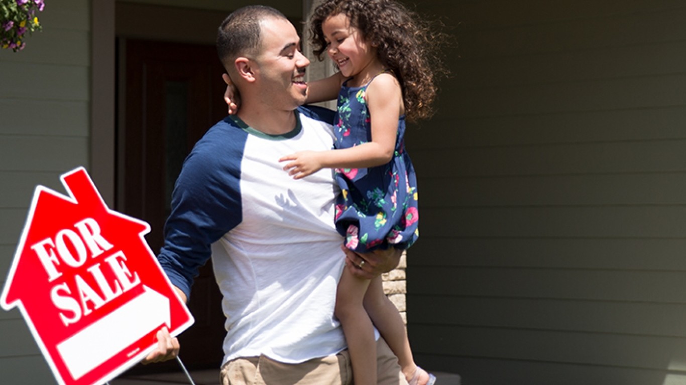 Daughter holding a house for sale sign and his daughter