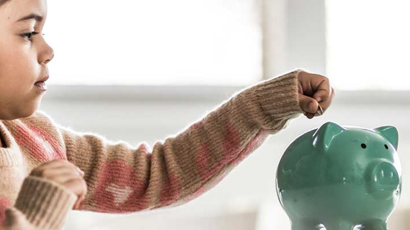 girl putting coin into piggy bank