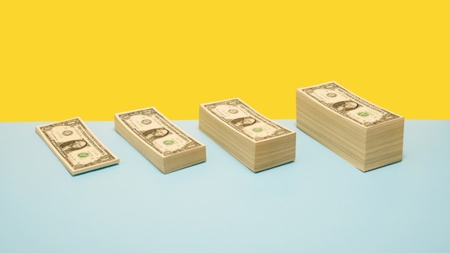 Four increasing stacks of dollar bills lined up in a row.