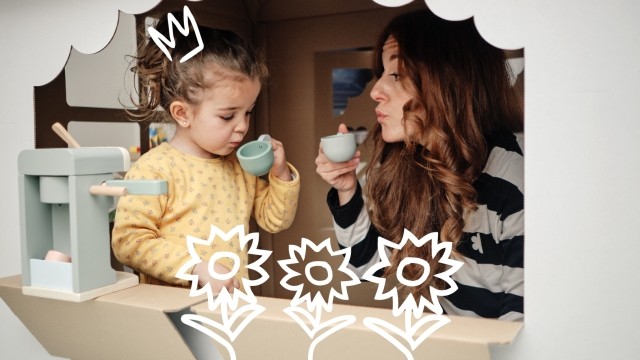 Woman and child pretending to drink tea from plastic cups in a playhouse