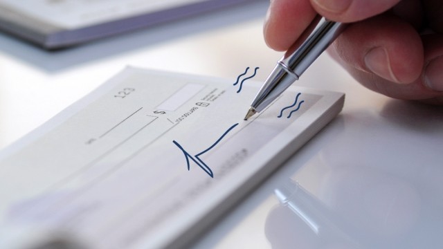 A paper check with a pen and hand