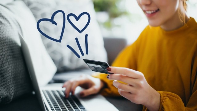 Woman holding a credit card with squiggle hearts in the air around her.