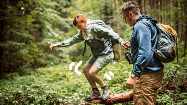 A man and a woman hike in a forested area with backpacks.