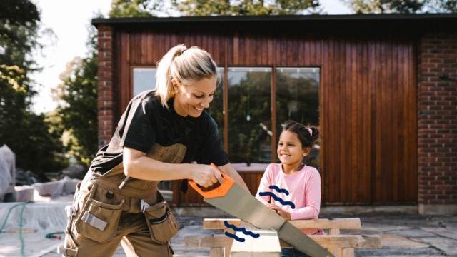 Woman using a saw to cup a piece of wood. 