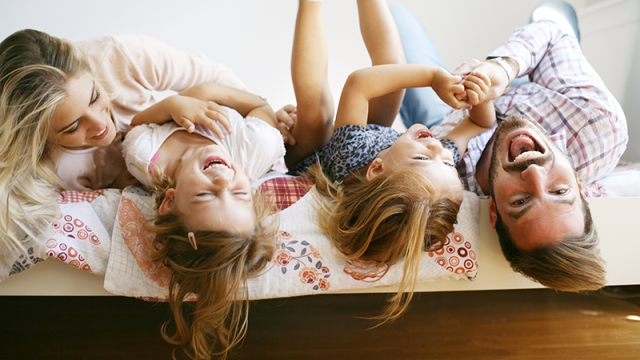 Family laughing on their bed