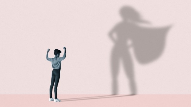 Person flexing muscles with superhero shadow casted on a wall