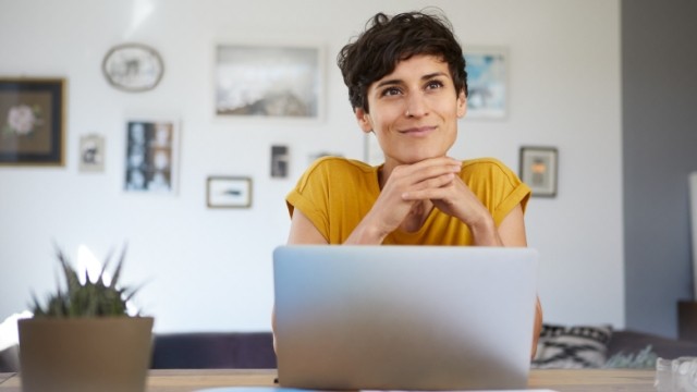 A content, short-haired person at home working on their laptop.