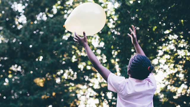 Girl in pink dress playing with a balloon