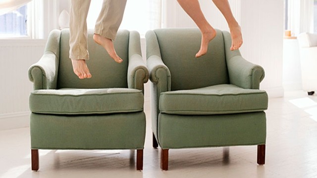 Two sets of barefoot feet jumping off armchairs.
