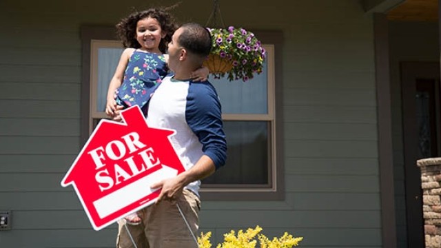 Father and daughter pulling for sale sign
