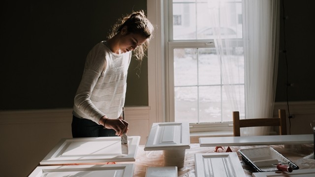 Woman painting cabinet doors