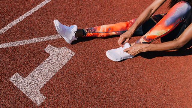 Runner lacing up shoes on the track
