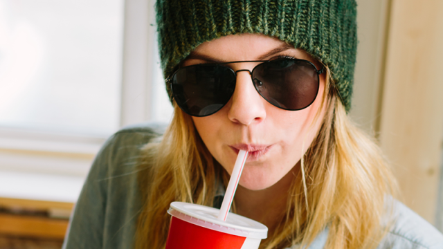 Young woman in sunglasses drinking a soda