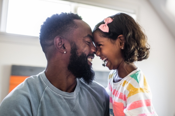  Father and daughter, grinning face to face.