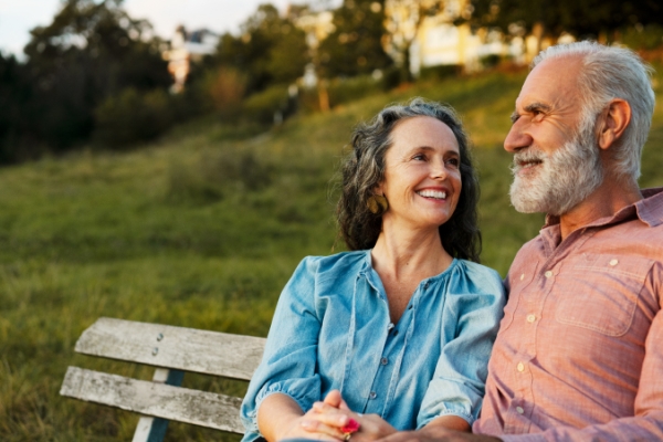 Retiree couple sitting on a park bench peacefully during golden hour in a park.    