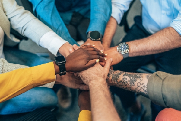 Nine people with hands in together as a team.