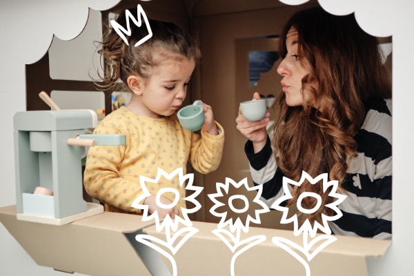 Woman and child pretending to drink tea from plastic cups in a playhouse