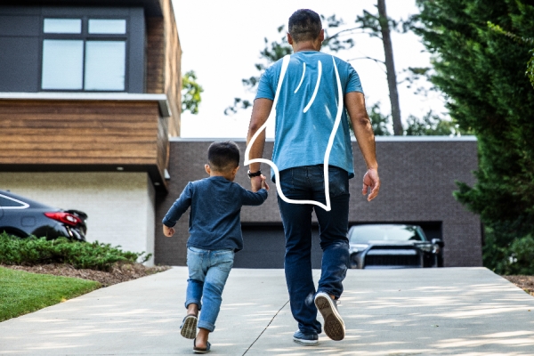 A Dad and his son, walking up a driveway. The Dad has a cape doodled on his back.  