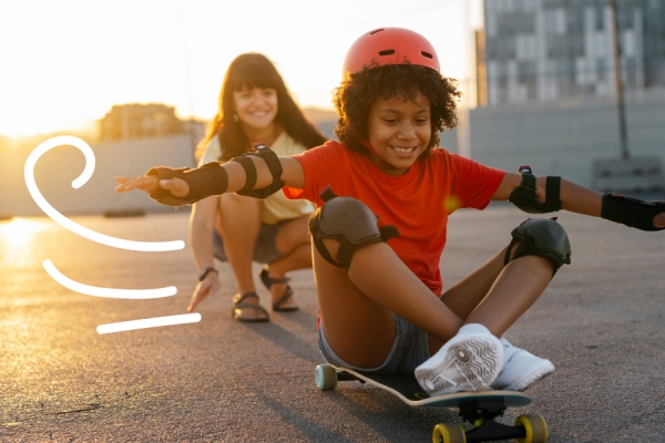 Child on a skateboard playing with their Mom. 