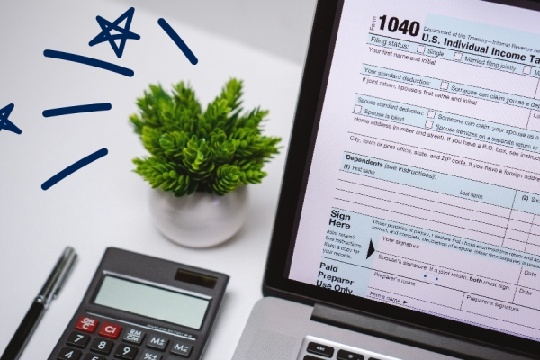 Plant on a desk next to a computer with a 1040 tax form displayed