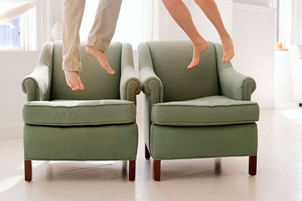 Two sets of barefoot feet jumping off armchairs.