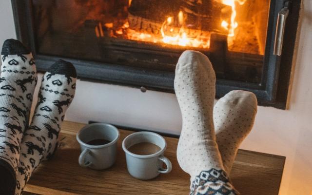 Image of feet warming by a cozy fireplace
