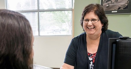 woman smiling working across a desk 