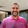Picture of OCCU Chief Operations Officer- Brian Alfano wearing a pink tee shirt.